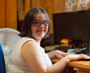 woman with down sydrome sitting on a desk using a laptop